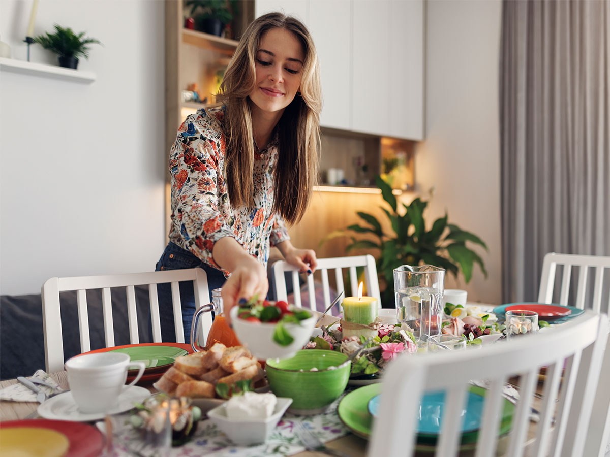 A woman arranging a table with vibrant, colorful plates in preparation for a meal