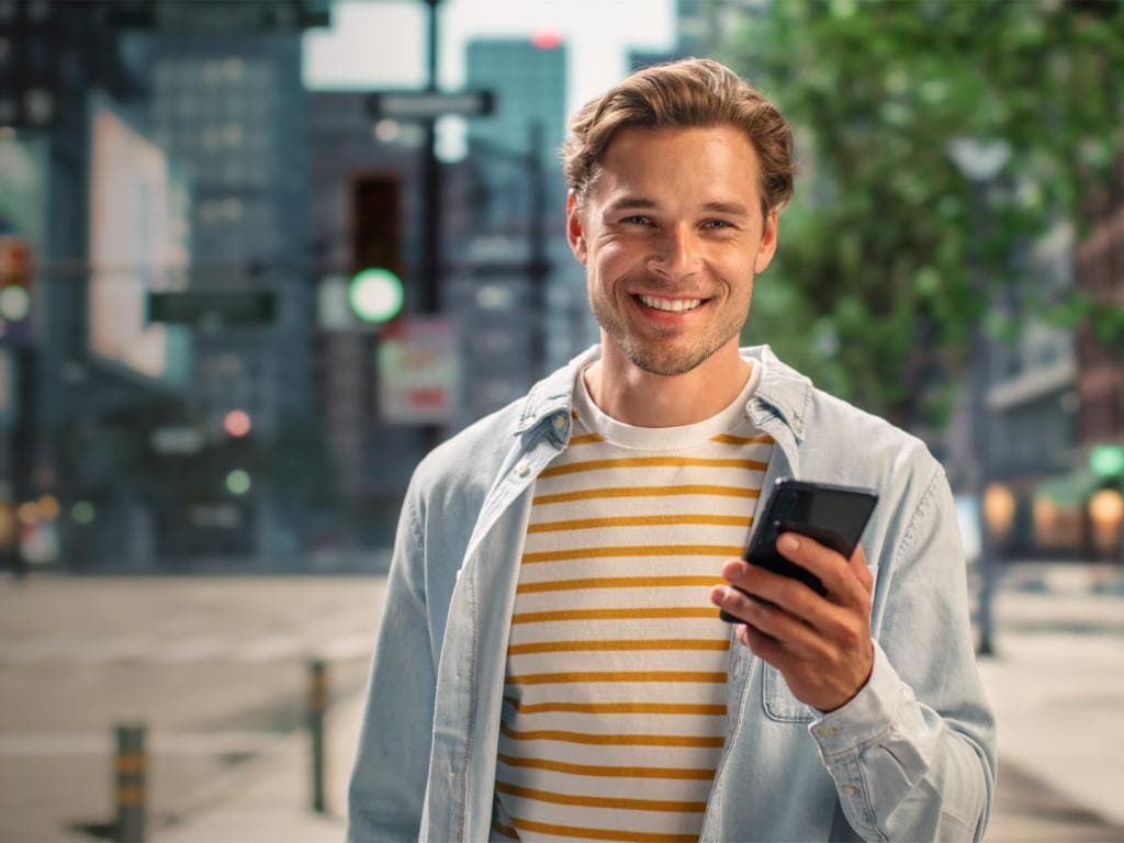 Young man smiling and holding a mobile phone