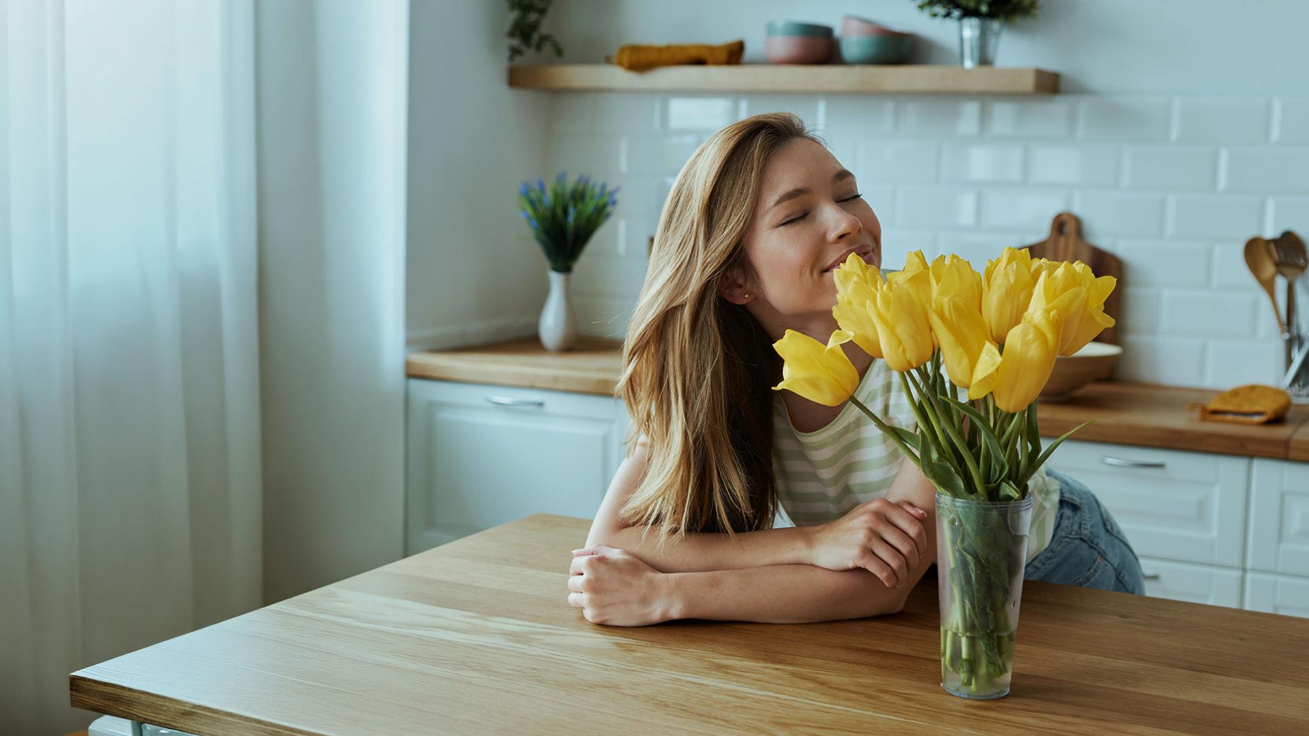 A woman sits at a table adorned with vibrant yellow tulips, creating a cheerful and inviting atmosphere
